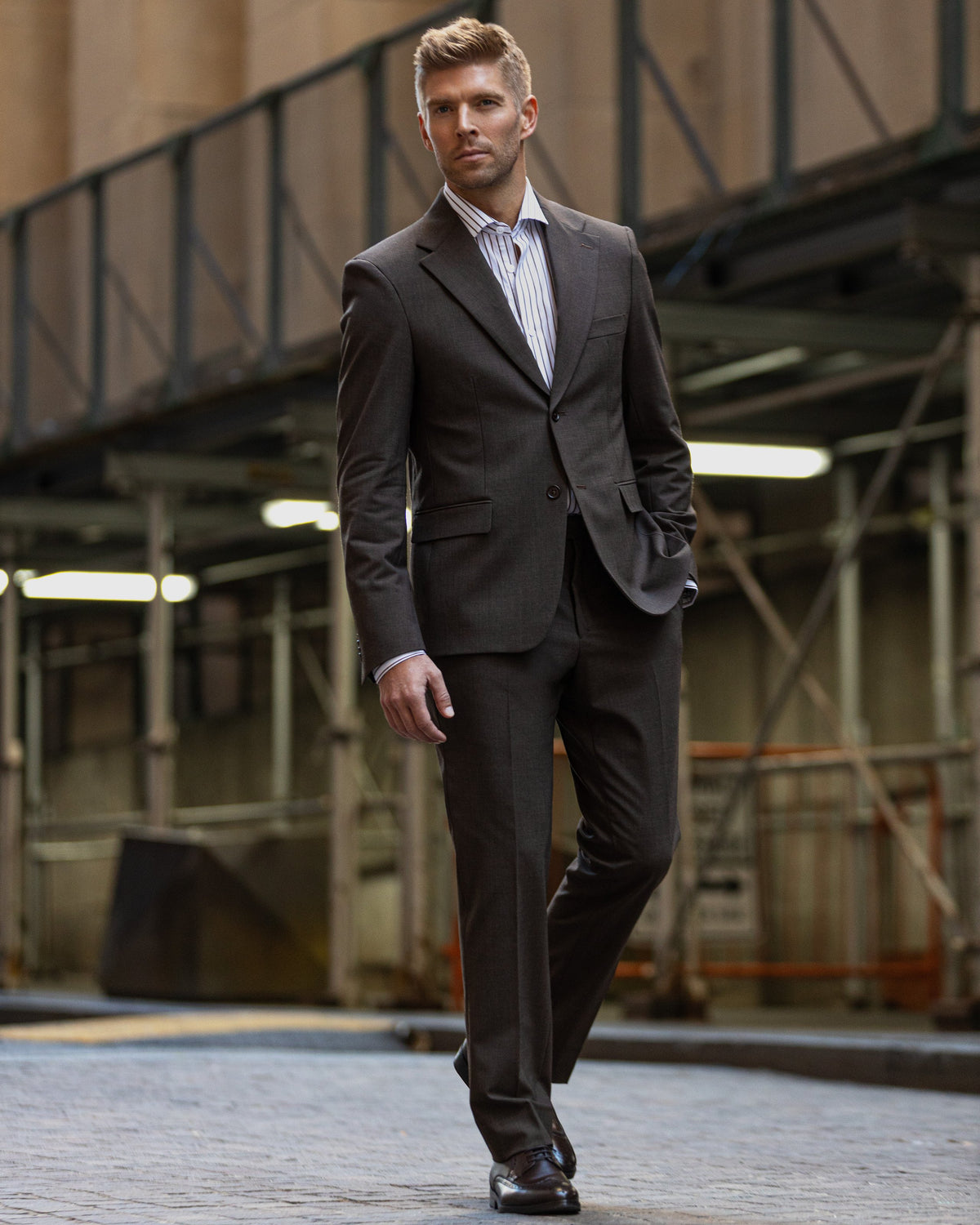 A man walking in a dark brown suit