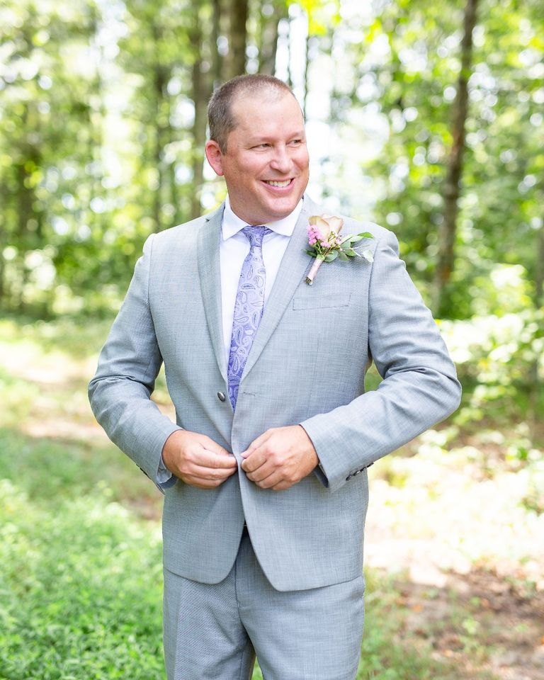 A groom in a light gray suit and lavender tie