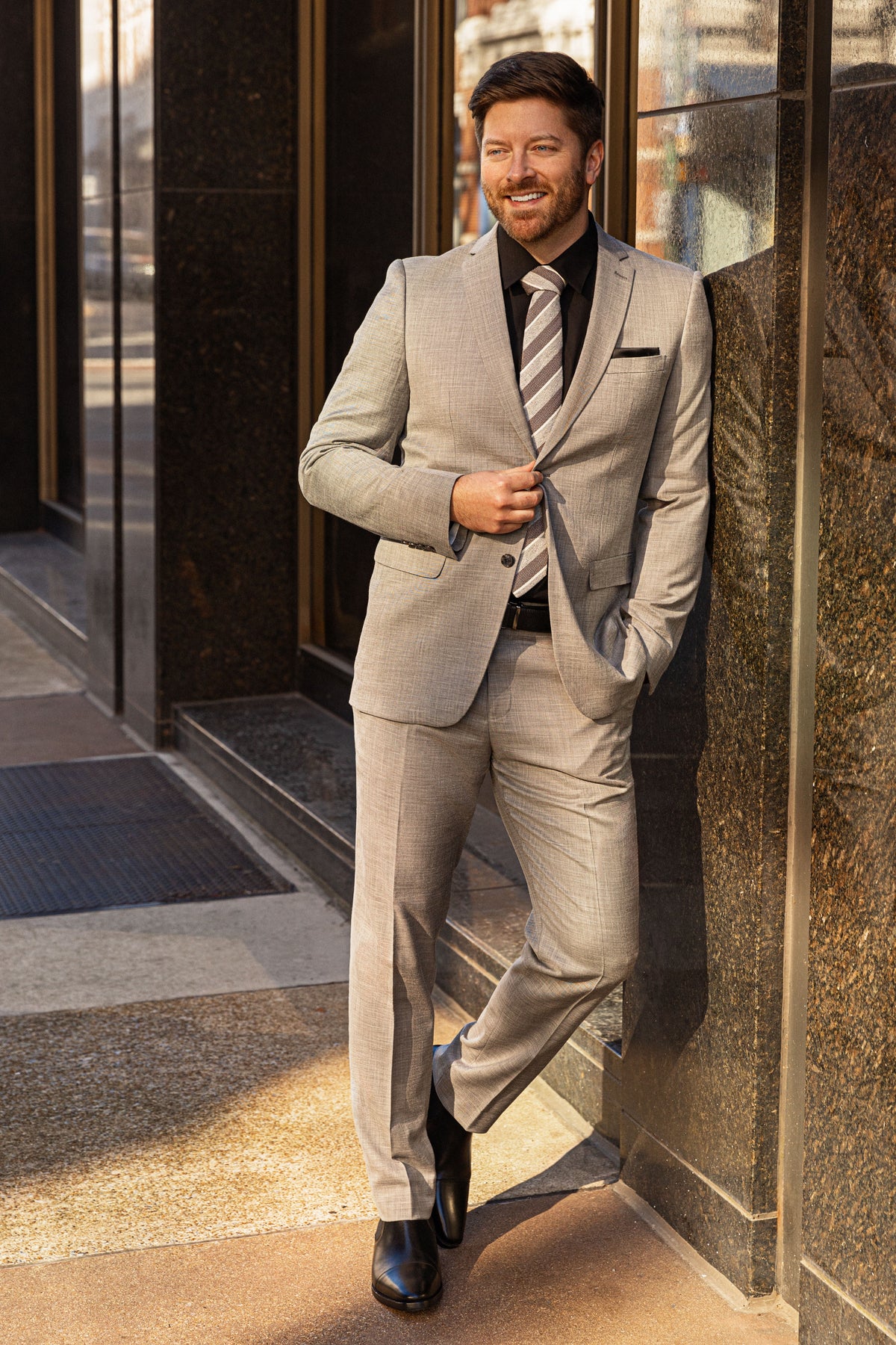 A smiling man in a light gray suit leaning in a doorway in downtown Chattanooga