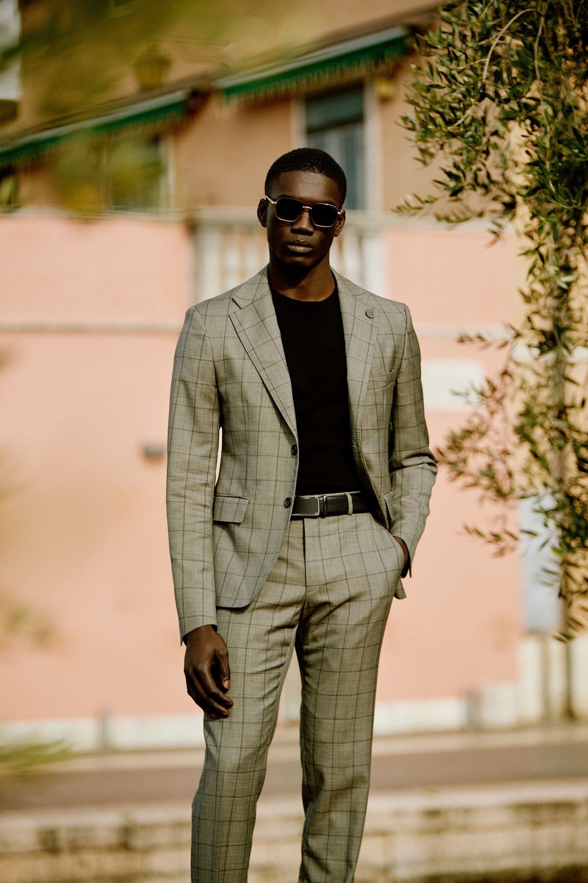A man in a check suit and black tee in an Italian courtyard