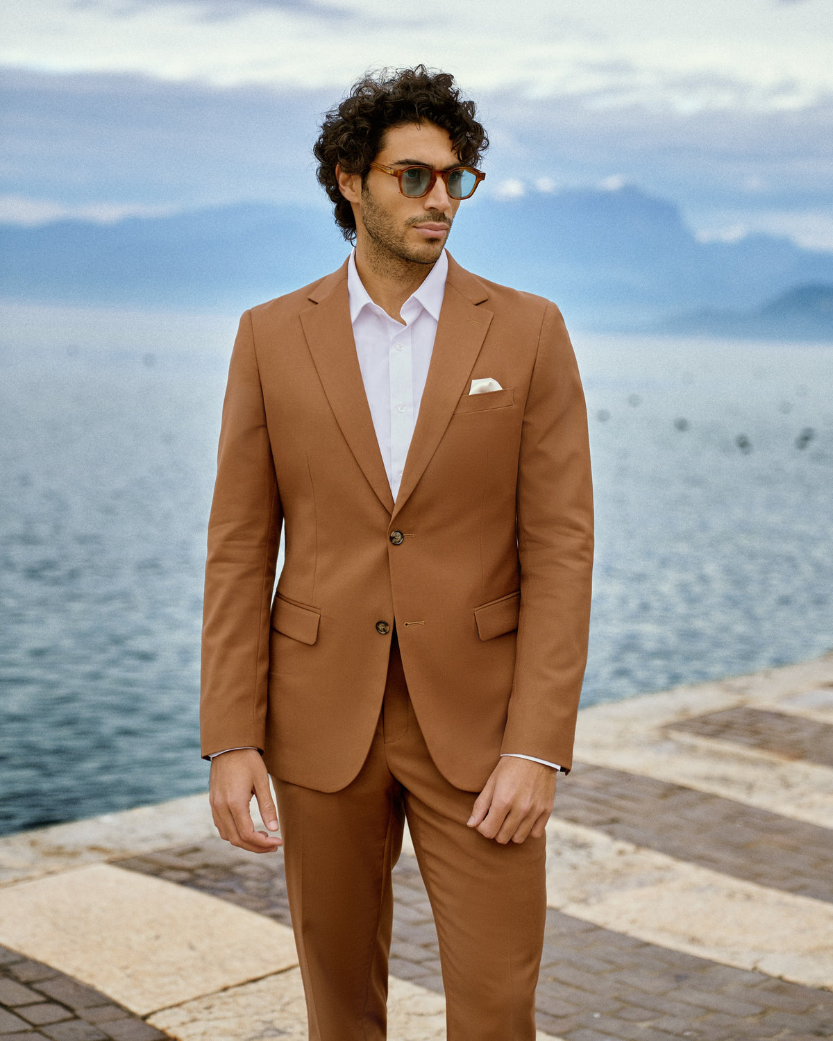 A man in a cognac suit and white shirt by Lake Garda, Italy