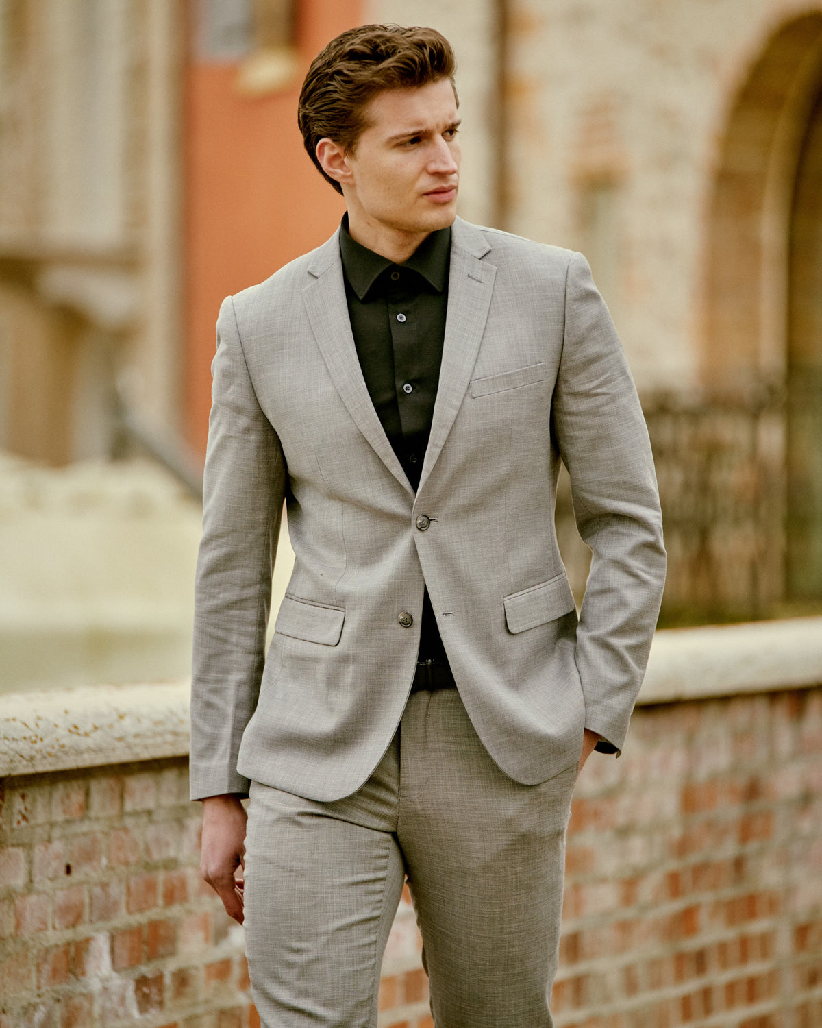 A man in a light gray suit and black shirt in Sirmione, Italy