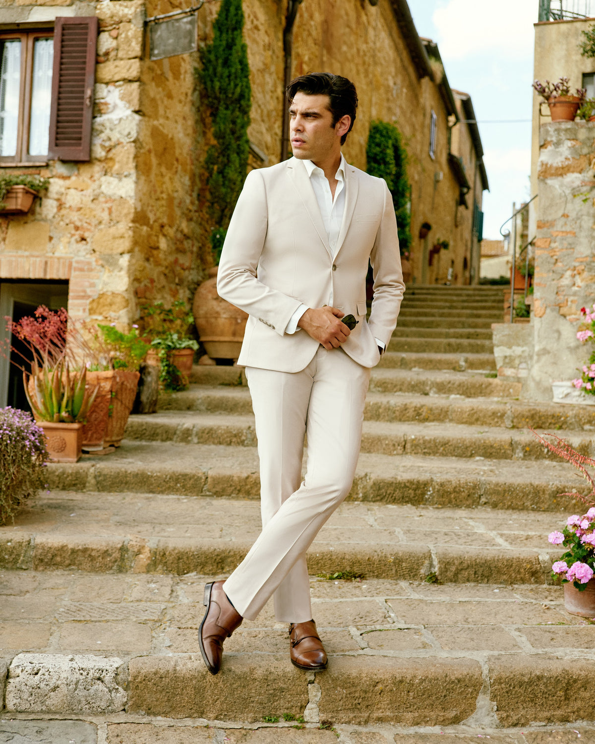 A man in an ivory suit walking down stone steps in Tuscany