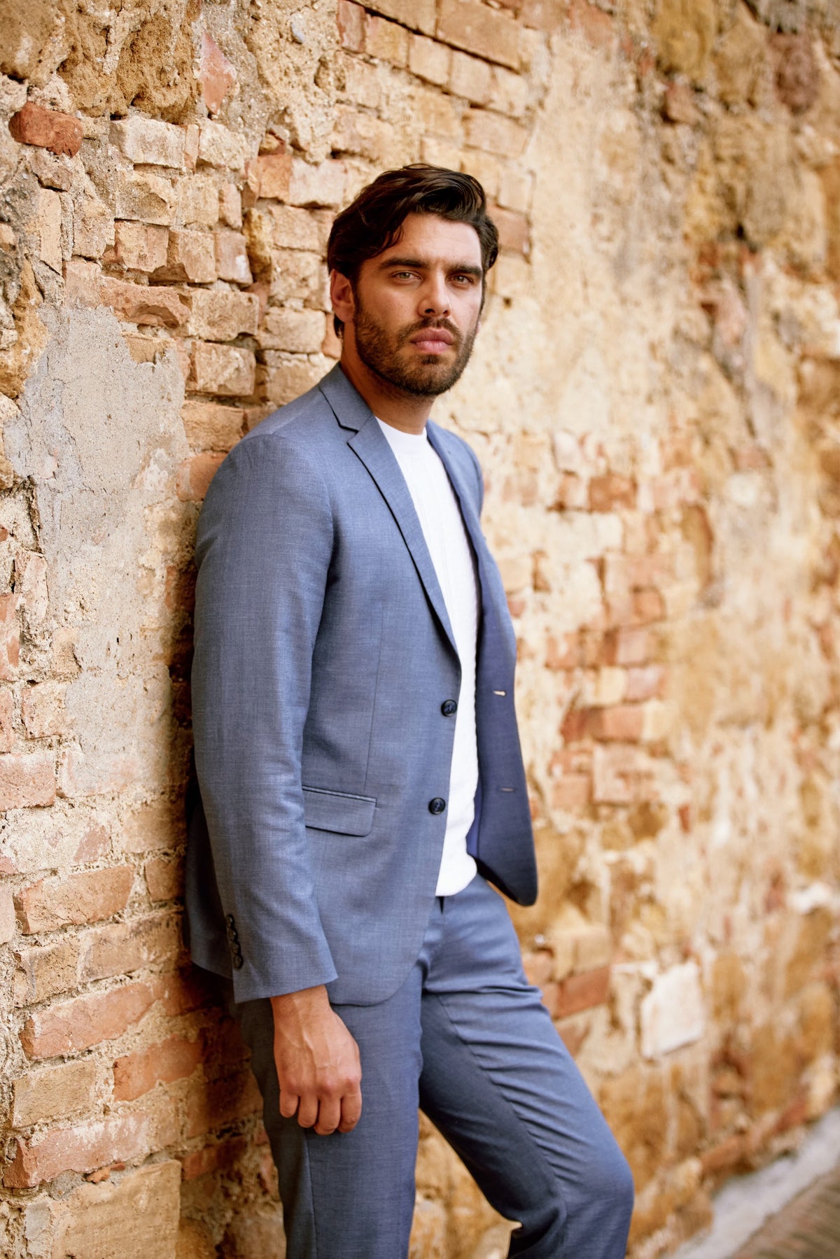 A man in a light blue suit and open-collar shirt in Tuscany