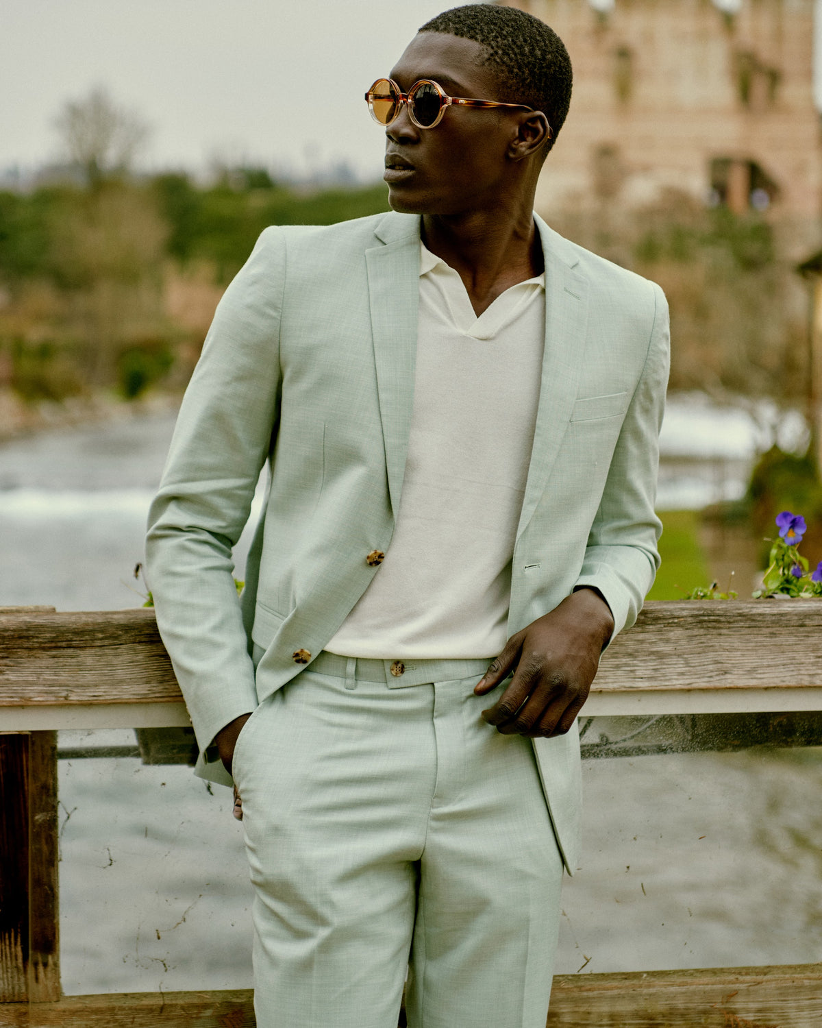 A man in a mint suit and sunglasses by the water in Sirmione