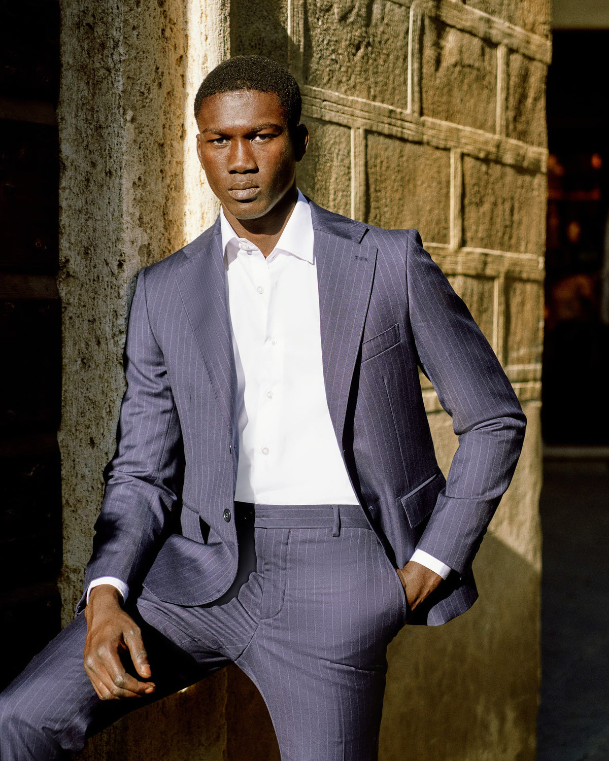 A man in a periwinkle blue suit seated in a Tuscan doorway