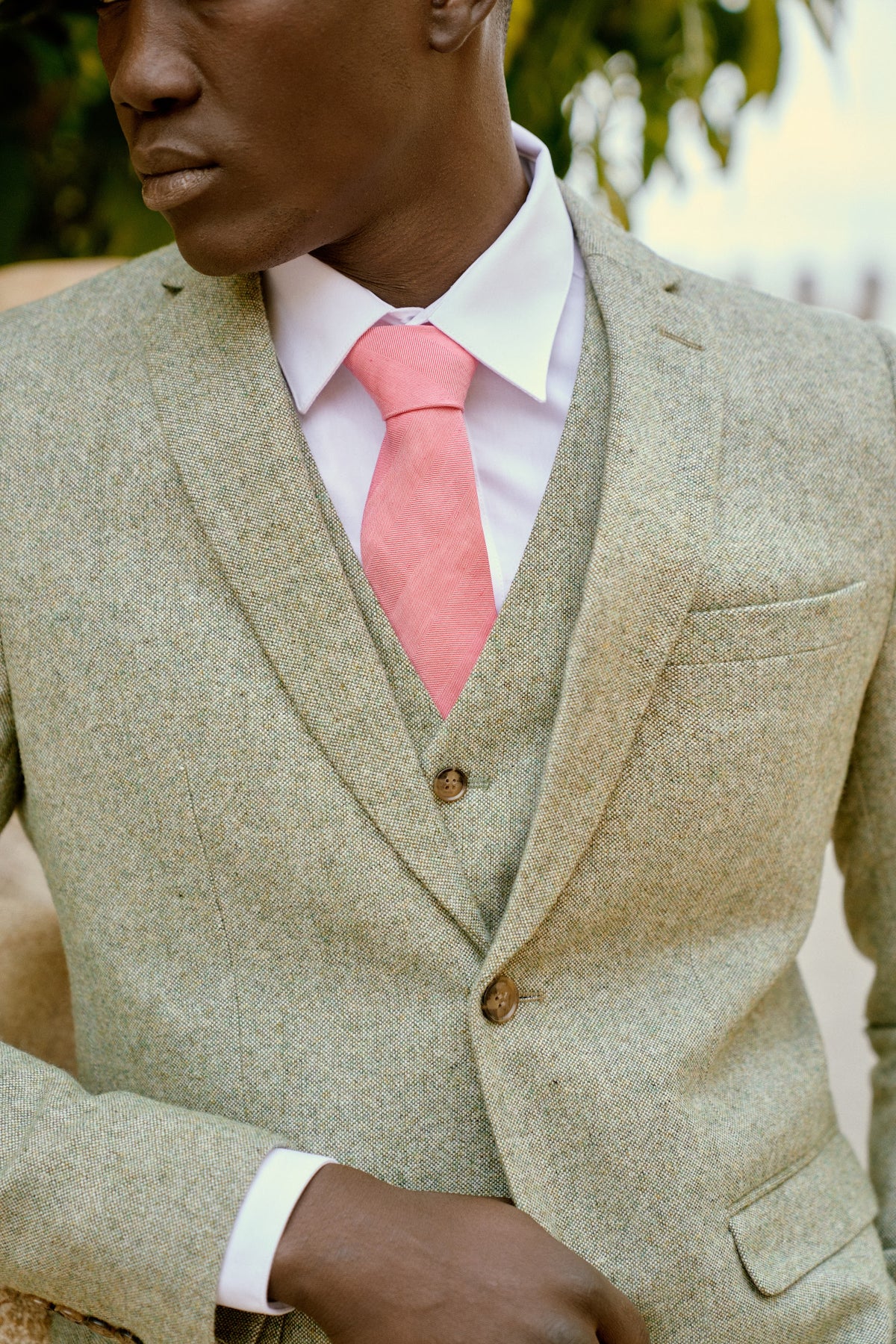 Close-up of a sand three-piece suit with a pink tie