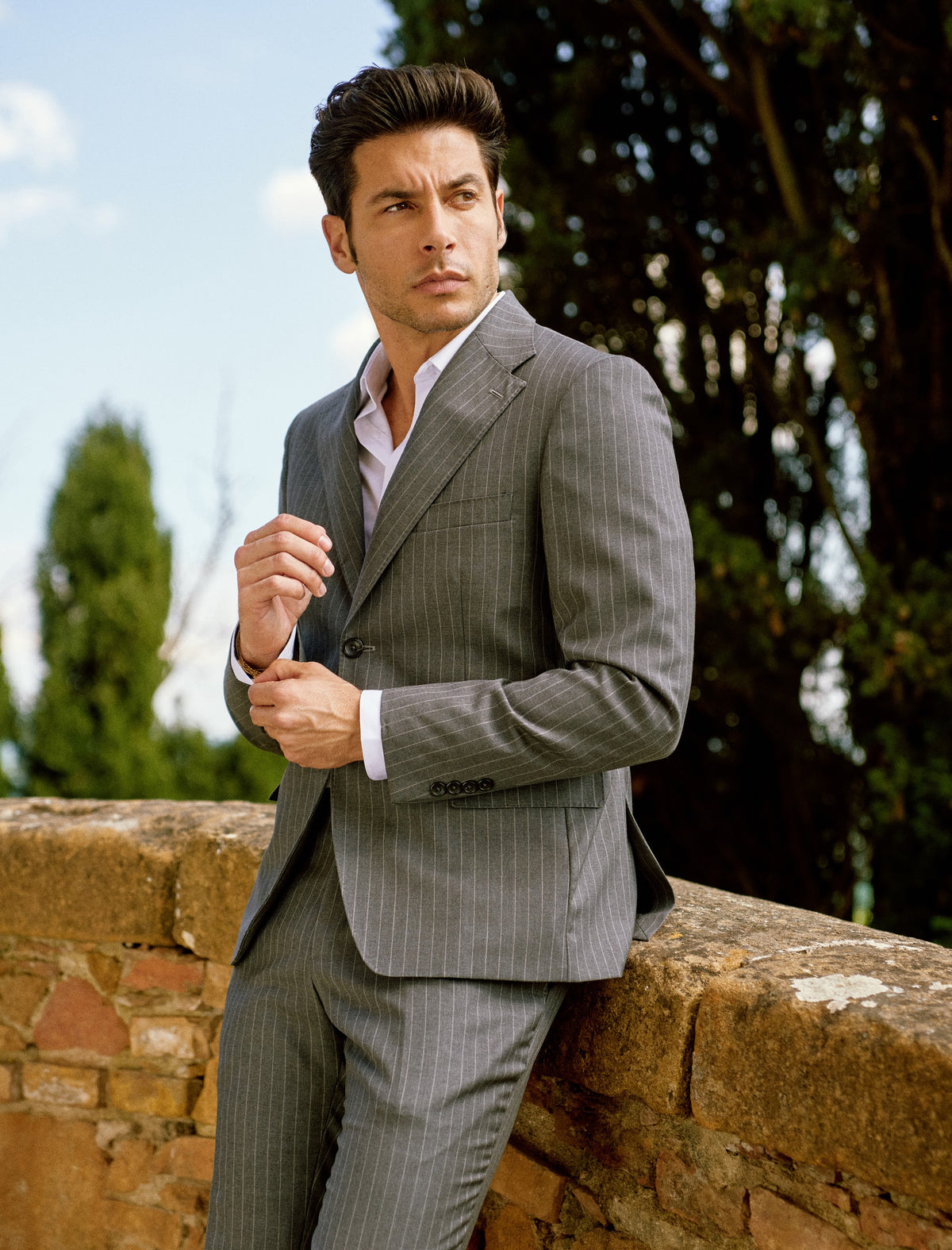 A man in a gray suit with cypress trees in Tuscany