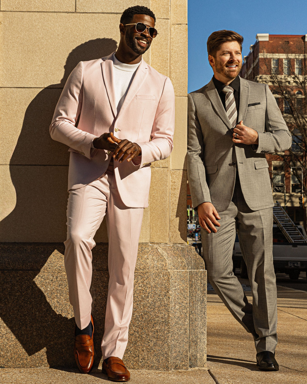 Two men, one in a blush suit and one in a gray suit