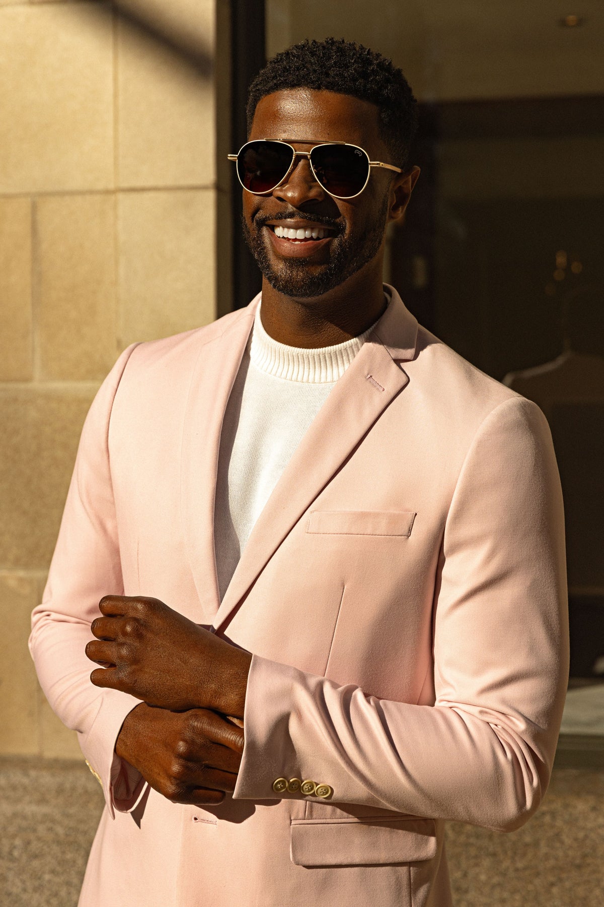 A smiling man in a blush suit, white tee and sunglasses in downtown Chattanooga