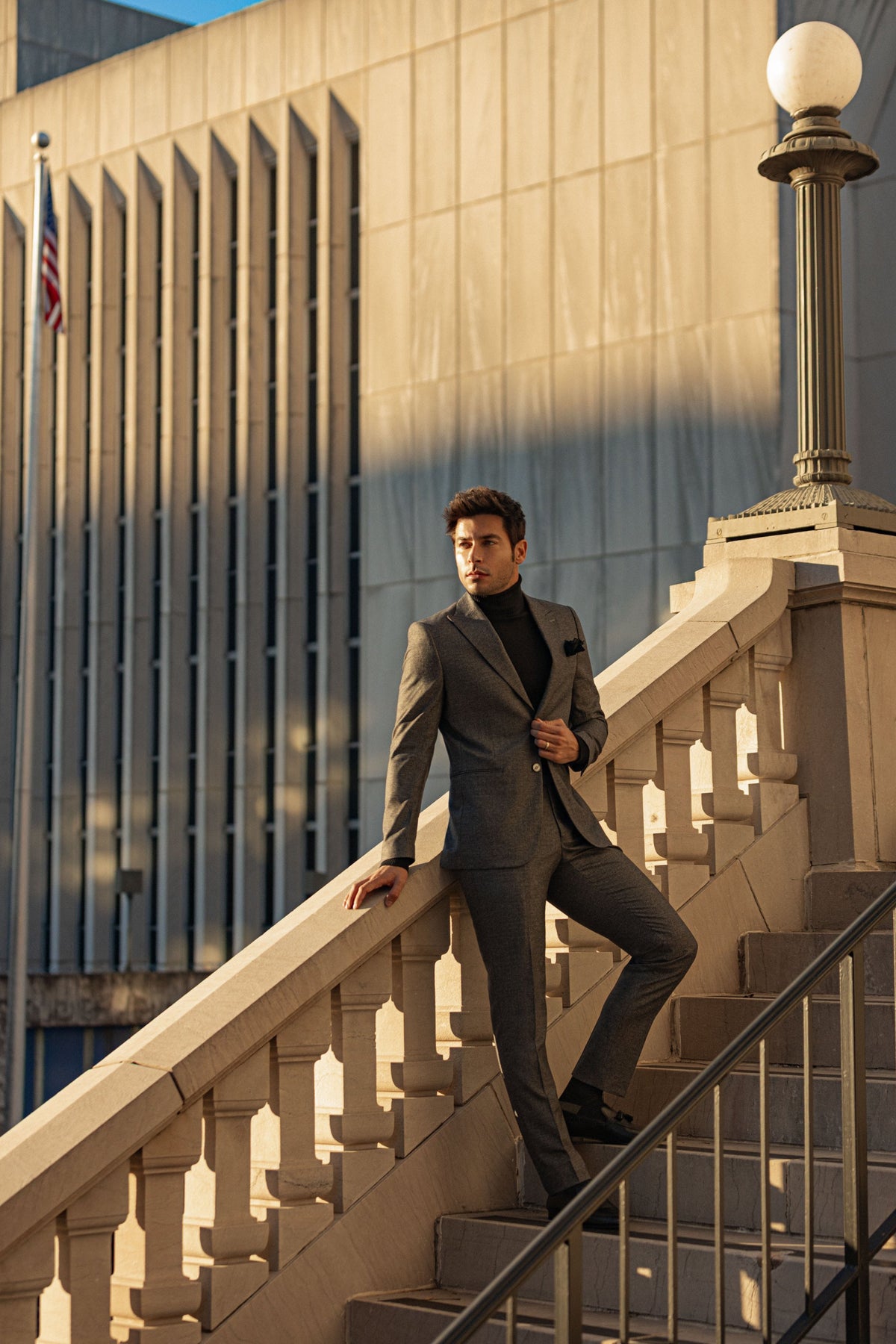 A man in a gray suit and turtleneck on a stone staircase