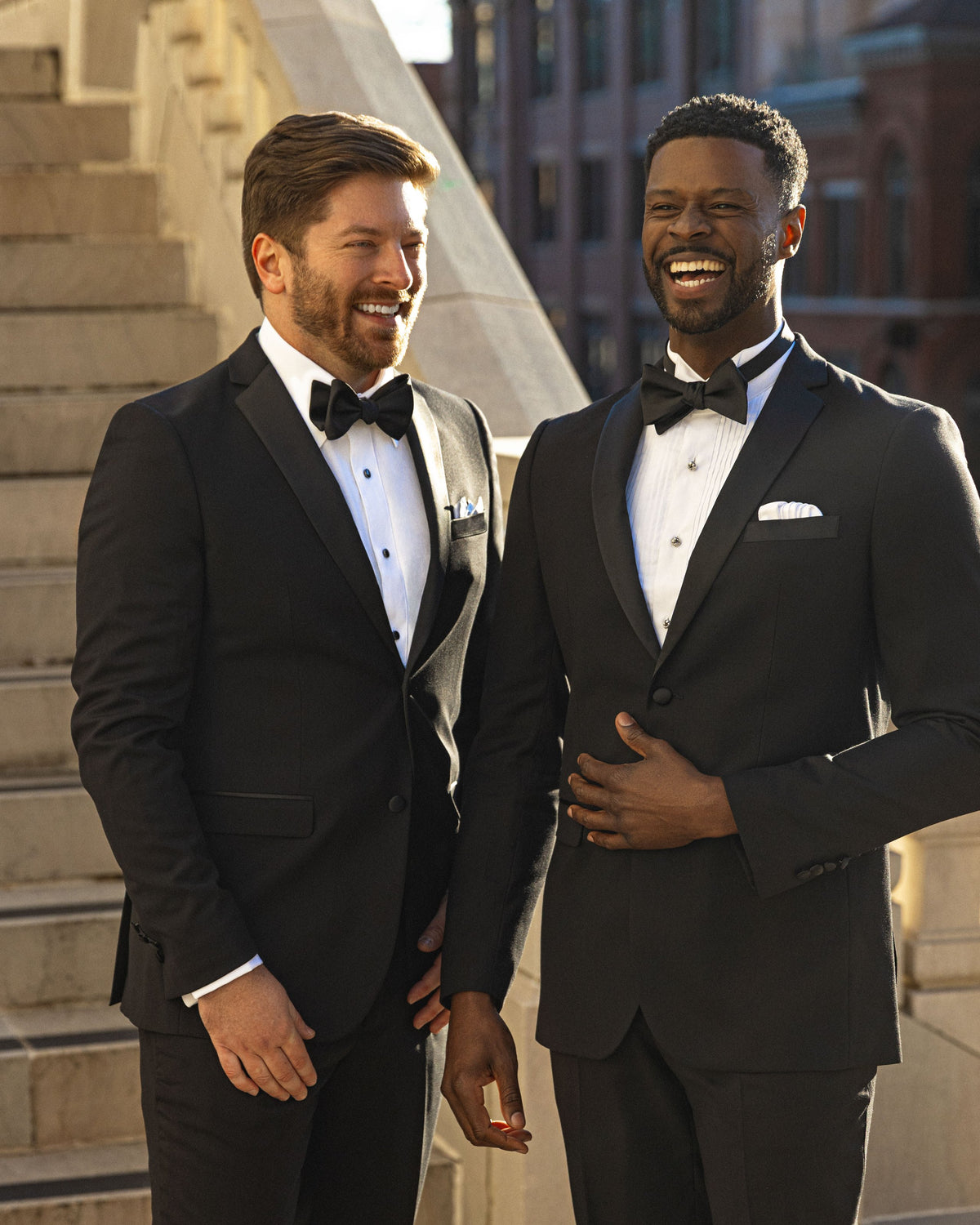 Two smiling men in black tuxedos